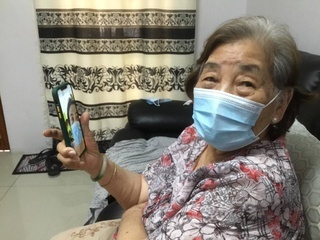 Elderly woman using smartphone to stay connected with family. Disclaimer: This image was captured during the global response to the COVID-19 pandemic. The contents of this image reflect the guidance communicated by local public health authorities at the time of its capture. Please note, public health guidance differs among countries and is indicative of the local context.