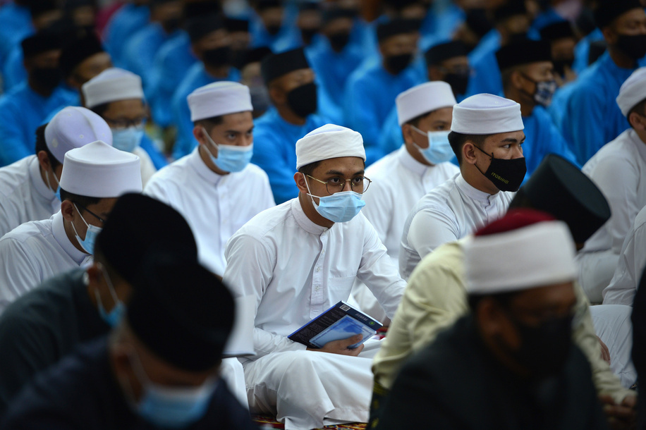 A Bruneian Muslim (C) reads a Quran at a mass prayer to celebrate the country's 37th National Day at Omar Ali Saifuddien mosque in the Brunei's capital, Bandar Seri Begawan prior to February 22, 2021. The authority imposes strict rules that all devotees to wear mask, scan QR codes, body temperature check and to bring own prayer mat to the mosque. Disclaimer: This image was captured during the global response to the COVID-19 pandemic. The contents of this image reflect the guidance communicated by local public health authorities at the time of its capture. Please note, public health guidance differs among countries and is indicative of the local context.