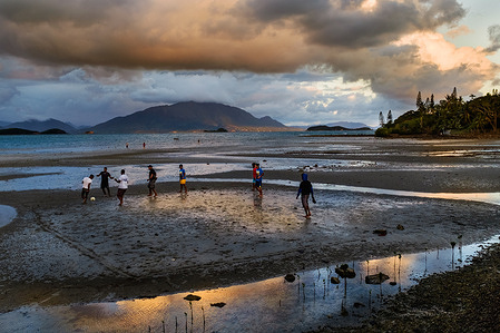 Youth takes advantage of low tide to play football on the sea bed in Noumea