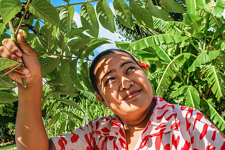 A health worker on a field visit shades herself from the sun with tree leaves.
